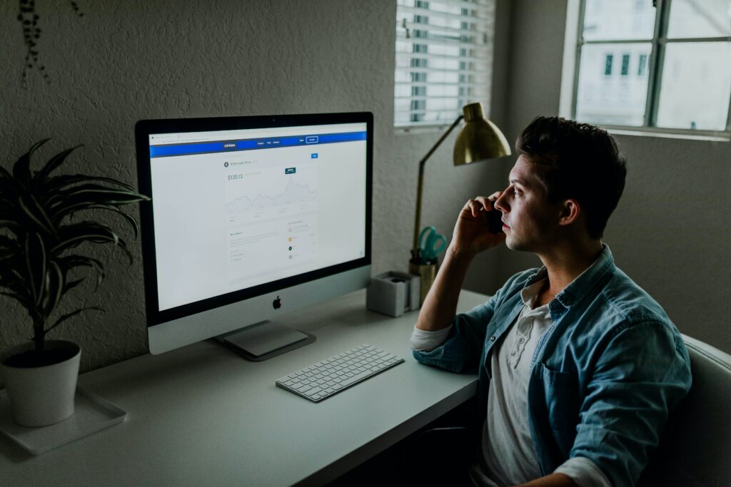 Hombre enfrente de un computador de escritorio revisando su perfil público en línea. 