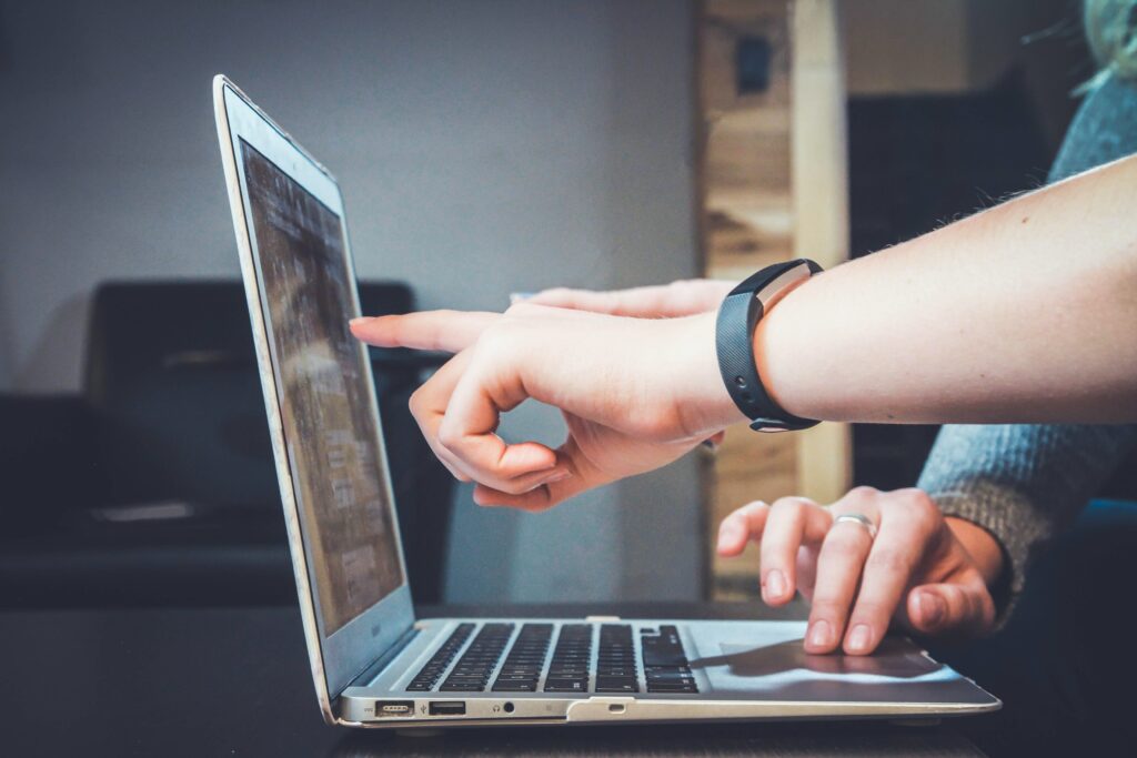 Dos personas señalando con sus dedos la pantalla de un computador portatil, mientras estudian sobre el byline guest posting. 
