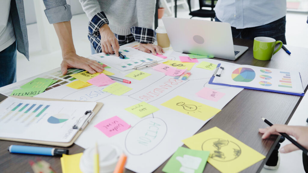 Grupo de trabajo en una oficina usando marcadores de colores para hacer un mapa conceptual sobre las relaciones públicas. 