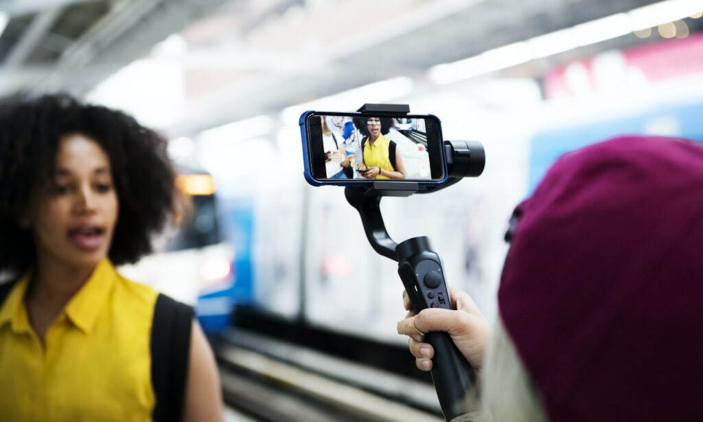 Mujer en la estación de metro grabando un video promocional para su página web