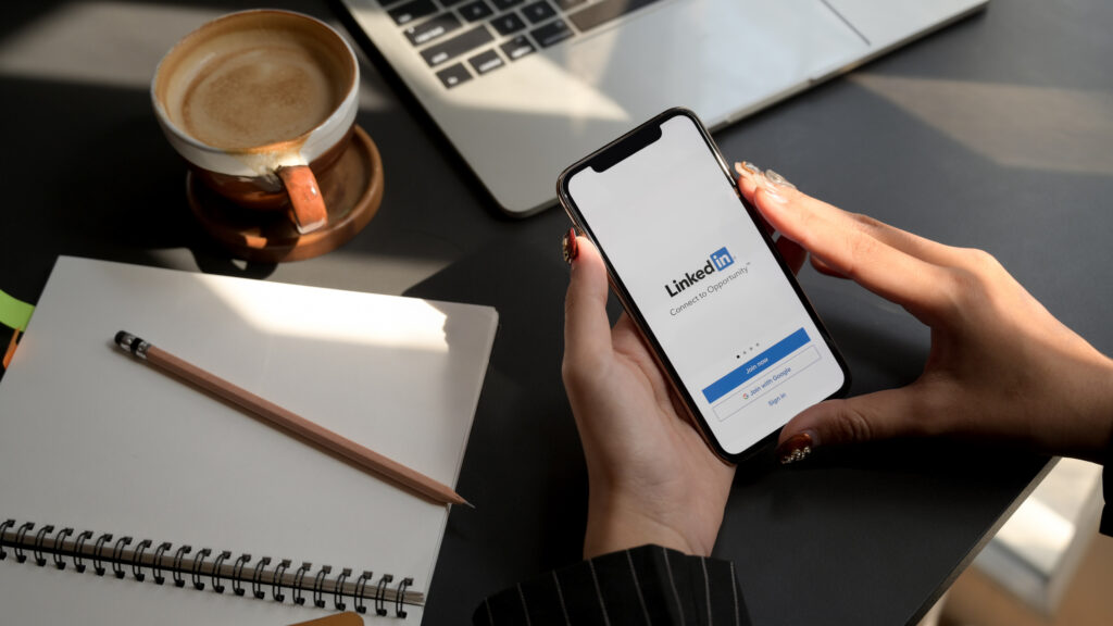 Mujer usando su telefono celular para crear una cuenta en LinkedIn y convertirse en una líder de opinión en línea.