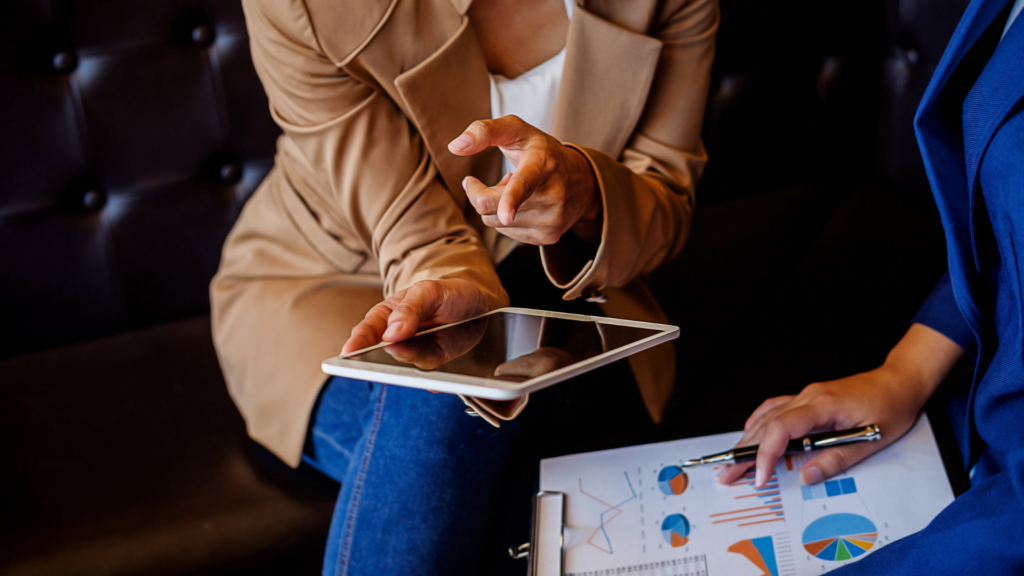 An image from an image bank depicting two people looking at statistics and holding a digital tablet, for an article about the importance of digital marketing in the pandemic era.