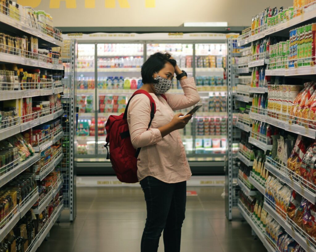 stock image of a woman shopping in a supermarket during the covid-19 pandemic.