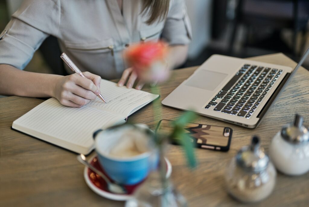 stock image of a woman writing in a notebook and looking at her aptop for an article about SEO tips for a blog.